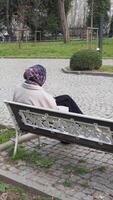 Woman in a scarf relaxing on a park bench in a city setting video
