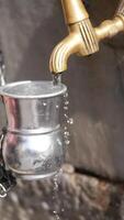 Pouring water from a tap into a metal pot in a rustic setting video