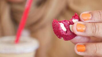 Enjoying a red velvet cookie with a beverage in a cozy setting video