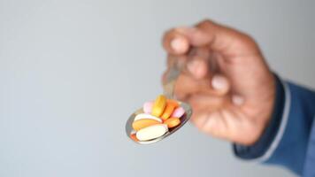 Hand holding a spoon with various colorful dietary supplements video