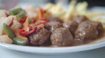 Savory meatballs with colorful vegetables served on a plate video