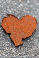 Rusty heart shape found on pavement, symbolizing love and resilience in urban environments. photo