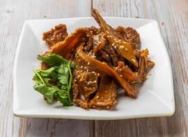 Braised Beef Tripe with a savory sauce sprinkled with sesame seeds and cilantro served in plate on Wood Table Close up Side view of Hong Kong food photo