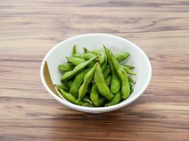 Edamame soybeans in pods served in bowl isolated on table top view of Japanese food photo
