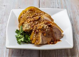 Spicy Sliced Cold Pork Hock with savory sauce, sesame seeds and cilantro served in plate on Wood Table Close up Side view of Hong Kong food photo