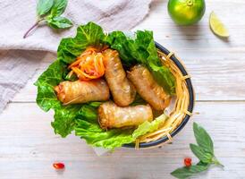 Vietnamese Fried Spring Rolls with lemon served in basket isolated on wooden background top view of Hong Kong food photo