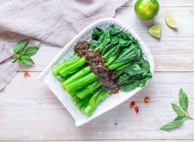 Chinese Broccoli or gai lan with Oyster Sauce with lemon served in plate isolated on wooden background top view of Hong Kong food photo