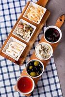 Labneh dips and sides with zaatar, shredded cheese, olives, yogurt, honey, and capsicum isolated on a wooden board top view of Middle Eastern appetizers and meze photo