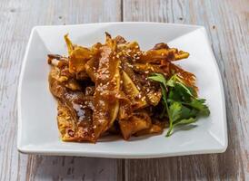 Spicy Pig Ear Salad with a spicy sauce, sprinkled with sesame seeds served in plate on Wood Table Close up Side view of Hong Kong food photo