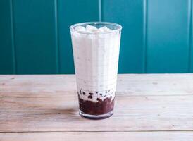 Iced red bean with coconut milk with ice cube served in glass isolated on wooden background side view of Hong Kong drink photo
