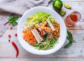 Shrimp and Vietnamese Sausage with Vietnam Vermicelli shrimp, rice vermicelli noodles, fresh vegetables, and crushed peanuts served in plate isolated on wooden background top view of Hong Kong food photo