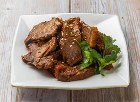 Spicy Sliced Taiwanese Beef with savory sauce, sesame seeds and cilantro served in plate on Wood Table Close up Side view of Hong Kong food photo