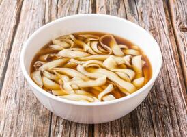 Sliced Noodles soup served in bowl isolated on wooden table side view of hong kong food photo