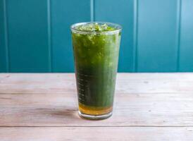 Iced Matcha Lemonade, Icepear and Centella Asiatica drink with ice cube served in glass isolated on wooden background side view of Hong Kong drink photo