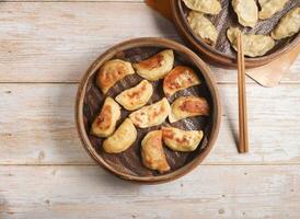 Handmade fried dumplings with steamed dumpling or momo served in wooden dish with chopsticks isolated on table top view Japanese food photo