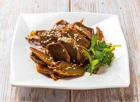 Braised Chicken Kidney with savory sauce, sesame seeds and cilantro served in plate on Wood Table Close up Side view of Hong Kong food photo