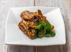 Marinated Goose Wings with savory sauce, sesame seeds and cilantro served in plate on Wood Table Close up Side view of Hong Kong food photo