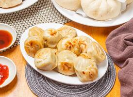 Shanghai Fried Buns or Momo with Dipping Sauce served in plate isolated napkin side view of chinese dim sum food photo