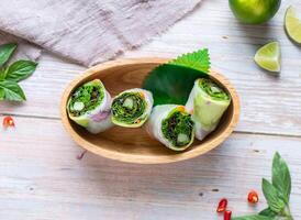 Avocado with Vietnamese Rice Paper Roll with lemon served in basket isolated on wooden background top view of Hong Kong food photo