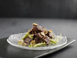 Stir-fried US Angus Beef Cube with Foie Gras Pate served in a dish side view on grey background photo