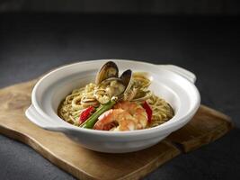 Stewed Ee Fu Noodles with Assorted Seafood served in a dish isolated on cutting board side view on dark background photo