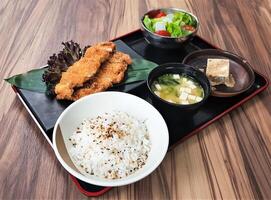 Tori Katsu Bento with chicken katsu, cutlet, rice, miso soup, tofu, and a side salad served on black tray isolated on table side view of Japanese cousin photo