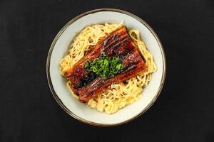 Unagi Don with grilled eel on rice nooldes, garnished with green onions served in bowl isolated on table top view of Japanese cousin photo