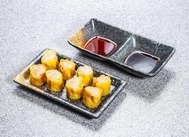 Coconut Shumai Dumplings with dipping sauces served in tray dish isolated on stone background side view of Asian Dim Sum Hong Kong photo