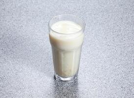 Homemade soy milk served in glass dish isolated on stone background side view of Asian Hong Kong drink photo