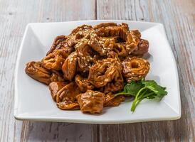 Braised Pork Intestines with a rich sauce, sprinkled with sesame seeds and fresh cilantro served in plate on Wood Table Close up Side view of Hong Kong food photo