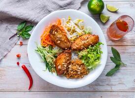 Garlic Chicken Wings with rice vermicelli noodles, fresh vegetables, and crushed peanuts served in plate isolated on wooden background top view of Hong Kong food photo