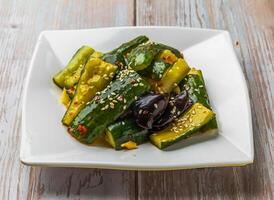 Spicy Cucumber Salad with sesame seeds and chili flakes served in plate on Wood Table Close up Side view of Hong Kong food photo