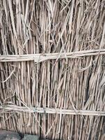 A wall made of sticks with a bench next to it photo