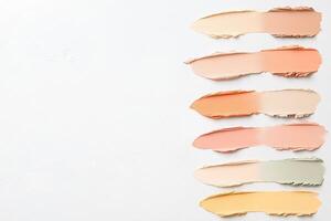A group of different colored concealer sticks on a white surface photo