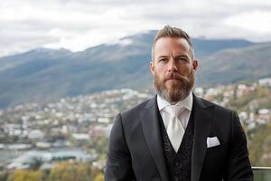 A man with a beard and suit standing in front of a mountain photo