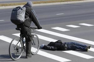 A man on a bike is standing next to a man laying on the ground photo