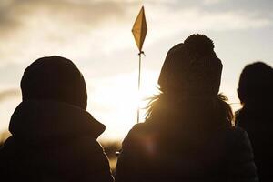 Three people are standing in the sun with a kite photo
