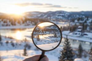 A person holding a magnifying glass over a snowy landscape photo