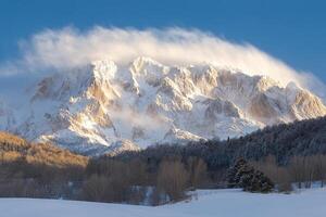 A snowy mountain covered in snow with a cloud in the sky photo