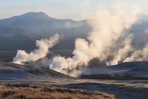 Steam rises from the ground in a field with mountains in the background photo