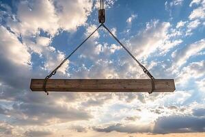 A wooden beam suspended in the air with a cloudy sky photo