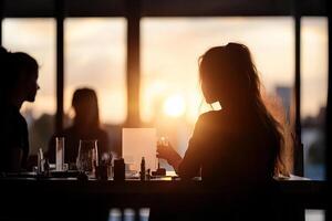 Silhouette of people sitting at a table with the sun setting behind them photo