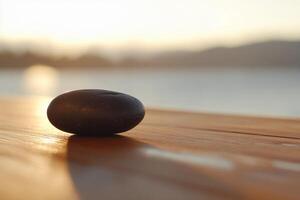 A stone sits on a wooden table in front of a lake photo