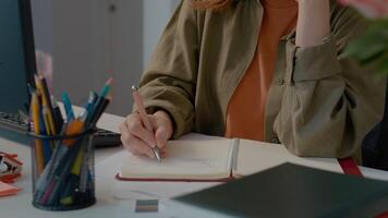 Woman takes notes during remote work at home office with a focused approach video