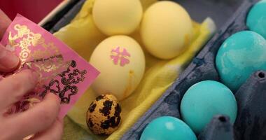 Process of decorating Easter eggs with stickers. This entertaining activity shows steps of egg painting in blue and yellow colors, focusing on colorful designs and unique decorations. video