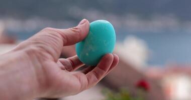 Hand shows blue turquoise Easter egg. Observe the techniques and details that bring color and excitement to this festive activity. video