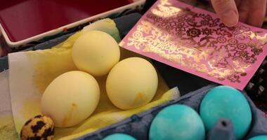 Learn the step of egg painting process while decorating Easter eggs with colorful stickers and blue yellow designs. Get inspired to create festive decorations this holiday season. video