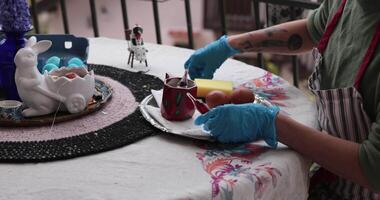 Enjoy a vibrant Easter egg painting session featuring various techniques and creative designs. Watch as hands delicately color and transform eggs at a cozy setting with family. video