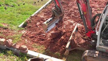 The excavators bucket is loaded with clay and stones as it digs into the earth. The powerful machine is at work on the construction site, preparing the ground for the next phase of the project. video