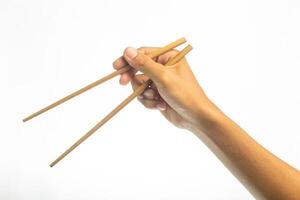 Ready to Eat with Chopsticks. A hand holding a pair of wooden chopsticks against a white background photo